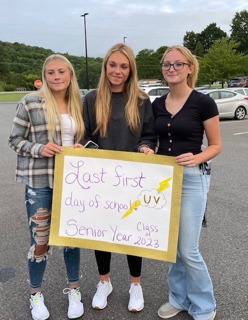 Three seniors hold a sign