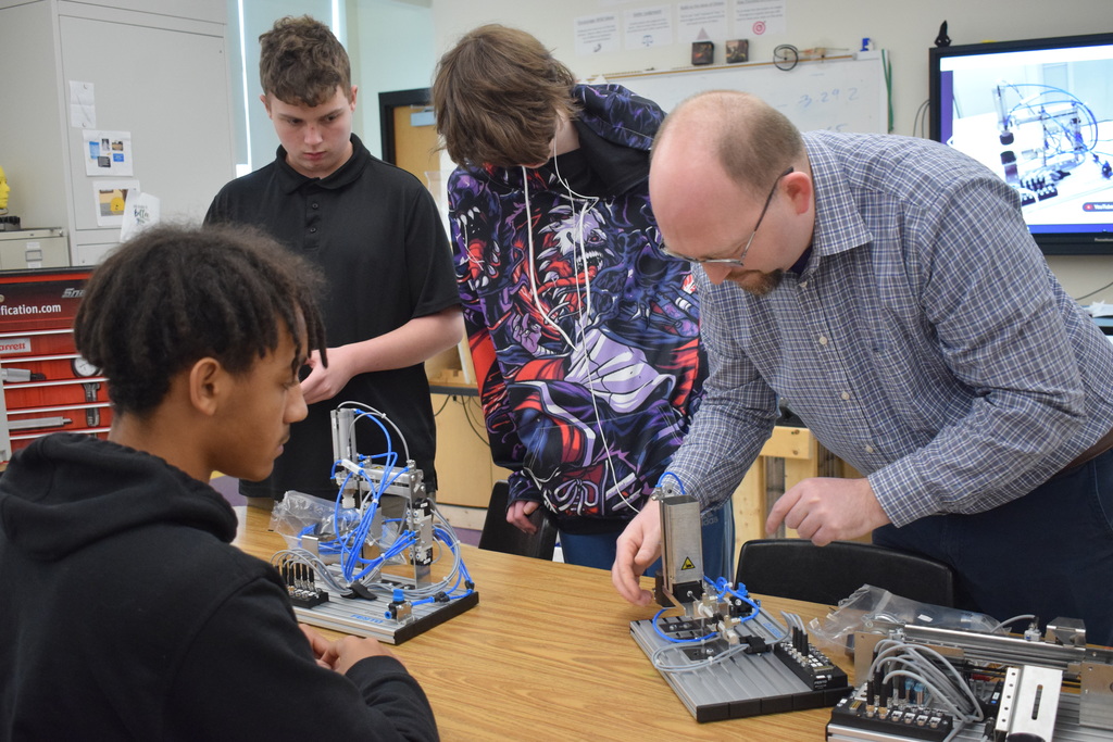 Three students and a teacher examine a device
